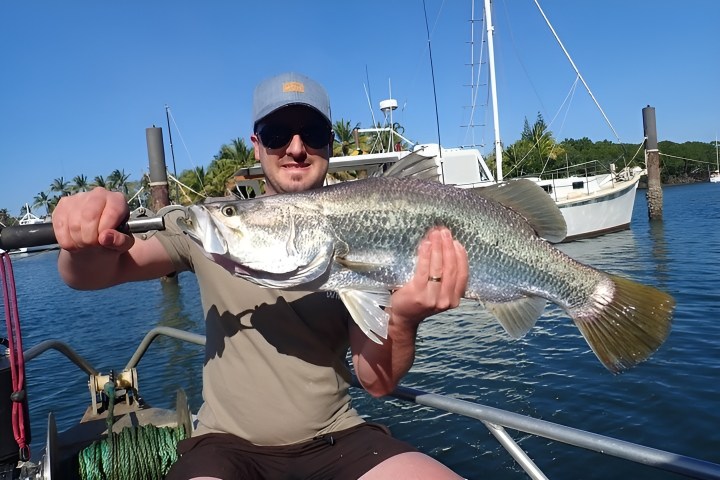 a person holding a fish on a boat in a body of water