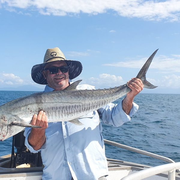 a person holding a fish on a boat in a body of water