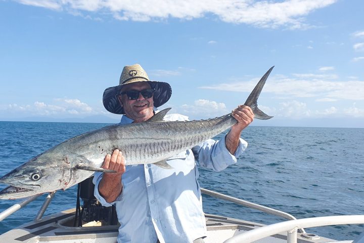 a person holding a fish on a boat in a body of water