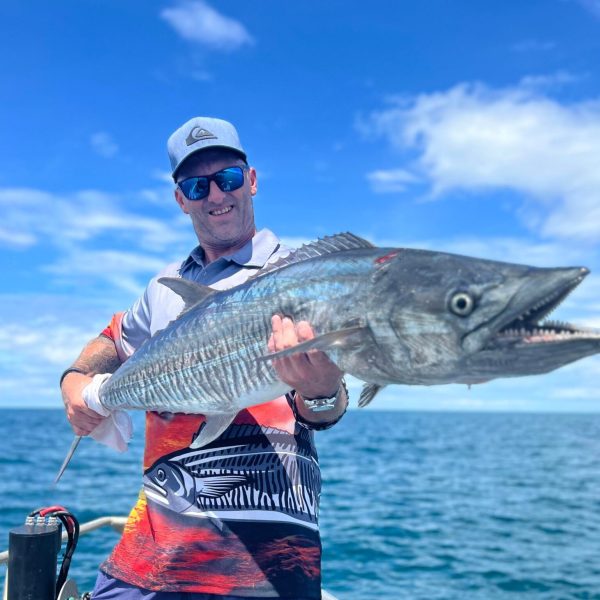 a man holding a fish on a boat in a body of water