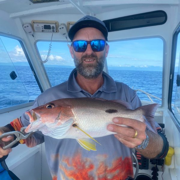 a man holding a fish on a boat in the water
